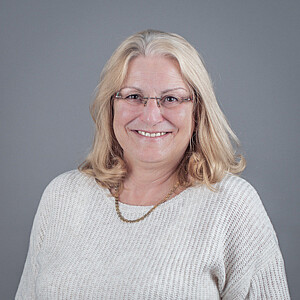 Porträt von Maria Schorn, eine Frau mit schulterlangen blonden Haaren und Brille